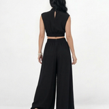 Enterizo negro cut out con cuello alto, hombrera estructurada, aberturas en cintura y pierna ancha con vuelo, elegante para eventos y salidas de noche