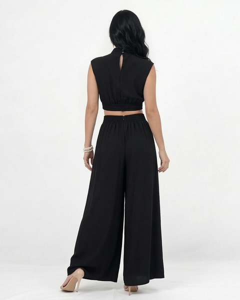 Enterizo negro cut out con cuello alto, hombrera estructurada, aberturas en cintura y pierna ancha con vuelo, elegante para eventos y salidas de noche