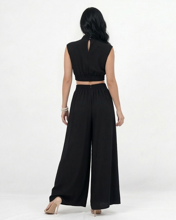 Enterizo negro cut out con cuello alto, hombrera estructurada, aberturas en cintura y pierna ancha con vuelo, elegante para eventos y salidas de noche