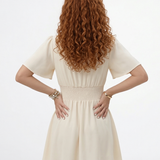 Vestido corto crema con escote en V cruzado, manga mariposa y falda con vuelo, perfecto para grados, matrimonios de día y salidas elegantes