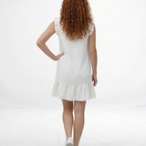 Vestido corto blanco en lino con escote en V, botones decorativos y volante en hombros y ruedo, ideal para vacaciones y planes de verano