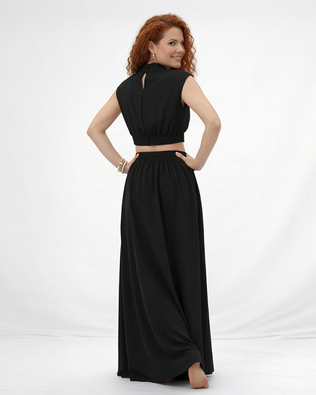 Vestido largo negro cuello alto con abertura cut out en cintura y falda acampanada fruncida, sofisticado y elegante para fiestas, grados y eventos especiales en Colombia