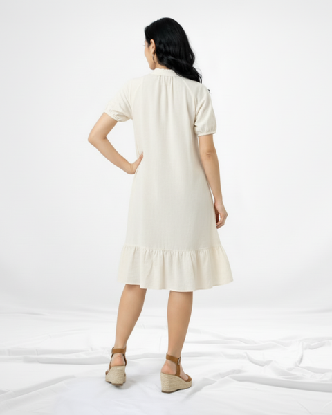 Vestido corto crema tipo camisero con cuello de camisa, manga corta globo, botones al frente y volante en el ruedo, fresco y casual para salidas de día y paseos