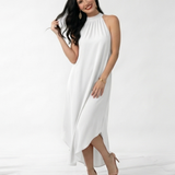 Vestido largo blanco con cuello halter fruncido, sin mangas, silueta suelta y ruedo asimétrico, ideal para matrimonios de día, grados y eventos especiales