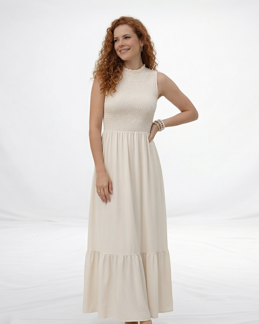 Vestido largo crema sin mangas con cuerpo fruncido, cuello alto y falda larga con volante escalonado, ideal para matrimonios de día, grados y eventos especiales
