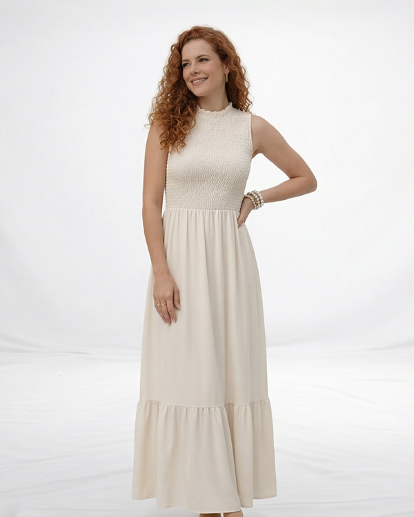 Vestido largo crema sin mangas con cuerpo fruncido, cuello alto y falda larga con volante escalonado, ideal para matrimonios de día, grados y eventos especiales