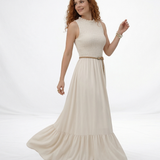 Vestido largo crema sin mangas con cuerpo fruncido, cuello alto y falda larga con volante escalonado, ideal para matrimonios de día, grados y eventos especiales