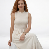 Vestido largo crema sin mangas con cuerpo fruncido, cuello alto y falda larga con volante escalonado, ideal para matrimonios de día, grados y eventos especiales