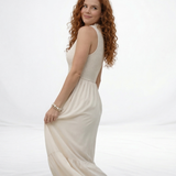 Vestido largo crema sin mangas con cuerpo fruncido, cuello alto y falda larga con volante escalonado, ideal para matrimonios de día, grados y eventos especiales