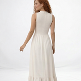 Vestido largo crema sin mangas con cuerpo fruncido, cuello alto y falda larga con volante escalonado, ideal para matrimonios de día, grados y eventos especiales