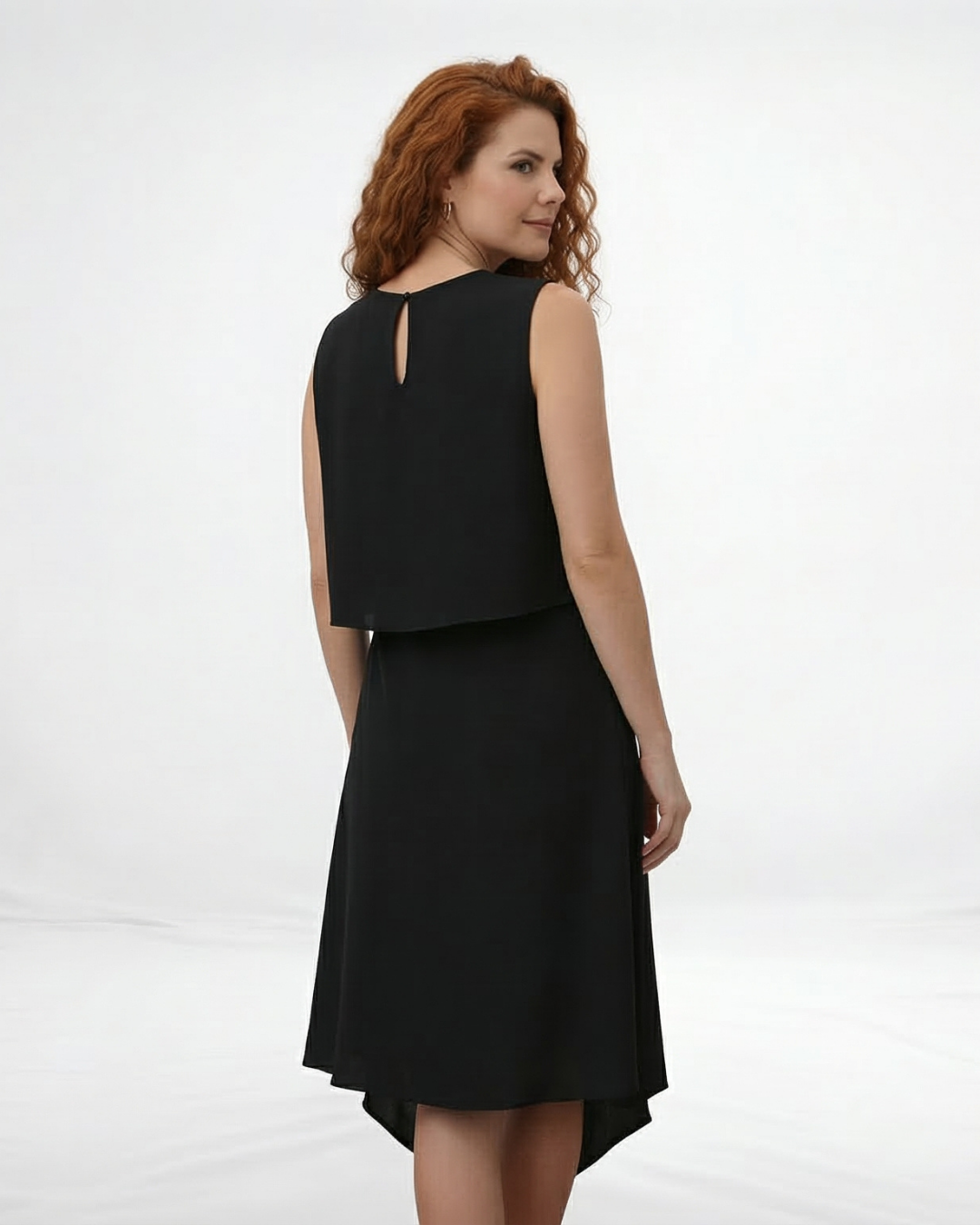Vestido midi negro sin mangas con cuello redondo, capa superior suelta y falda asimétrica cruzada con punta, elegante y moderno para eventos formales y salidas de noche