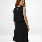 Vestido midi negro sin mangas con cuello redondo, capa superior suelta y falda asimétrica cruzada con punta, elegante y moderno para eventos formales y salidas de noche